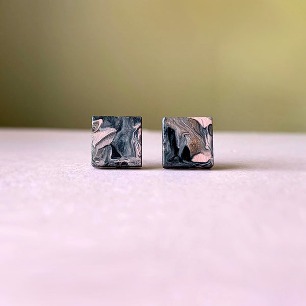 Square wood stud earrings with a marbled design painted in gray, black, rose, white, and shimmery rose gold